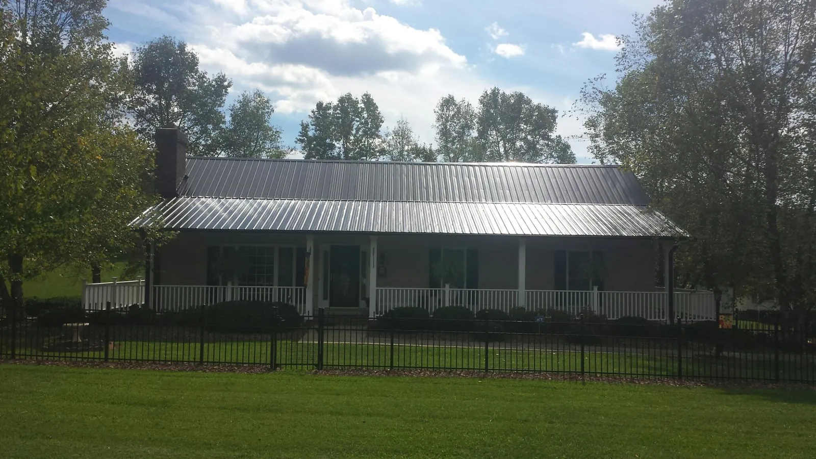 Gray metal roof on a brick ranch with a full width front porch — Gutter Guard Installation work by our crew in Vernon