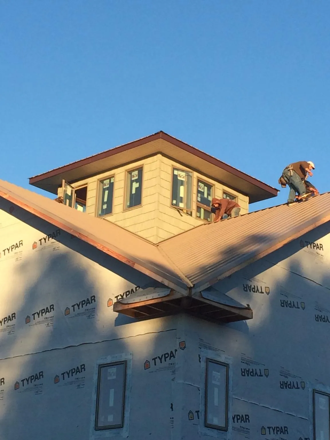 Roofers working around a rooftop cupola on a new metal roof at sunset — Roof Waterproofing in Vernon by Roofing Brothers